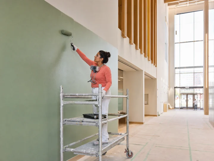 A commercial painter applying a colourful finish inside a new building.